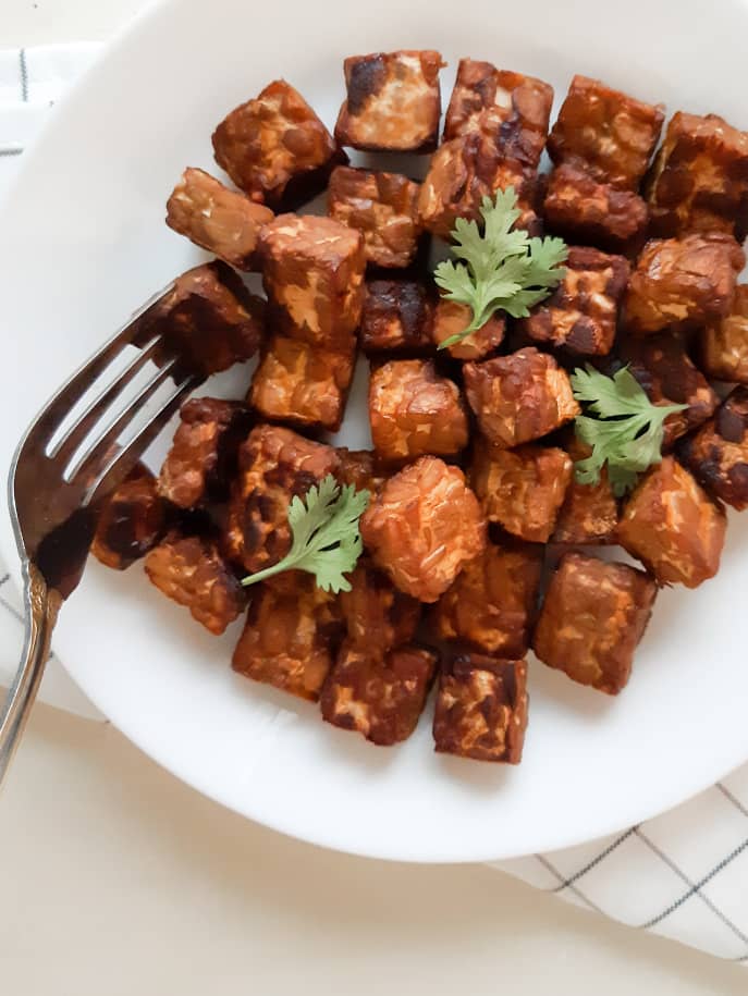 A close up shot of a fork forking out a piece of tempeh