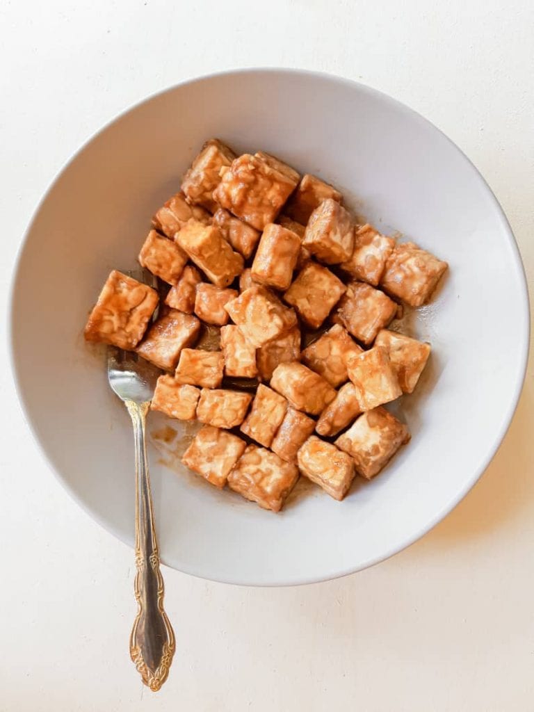 Tempeh marinating in a purple deep plate