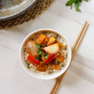 Stir-fry served with some brown rice in a white bowl