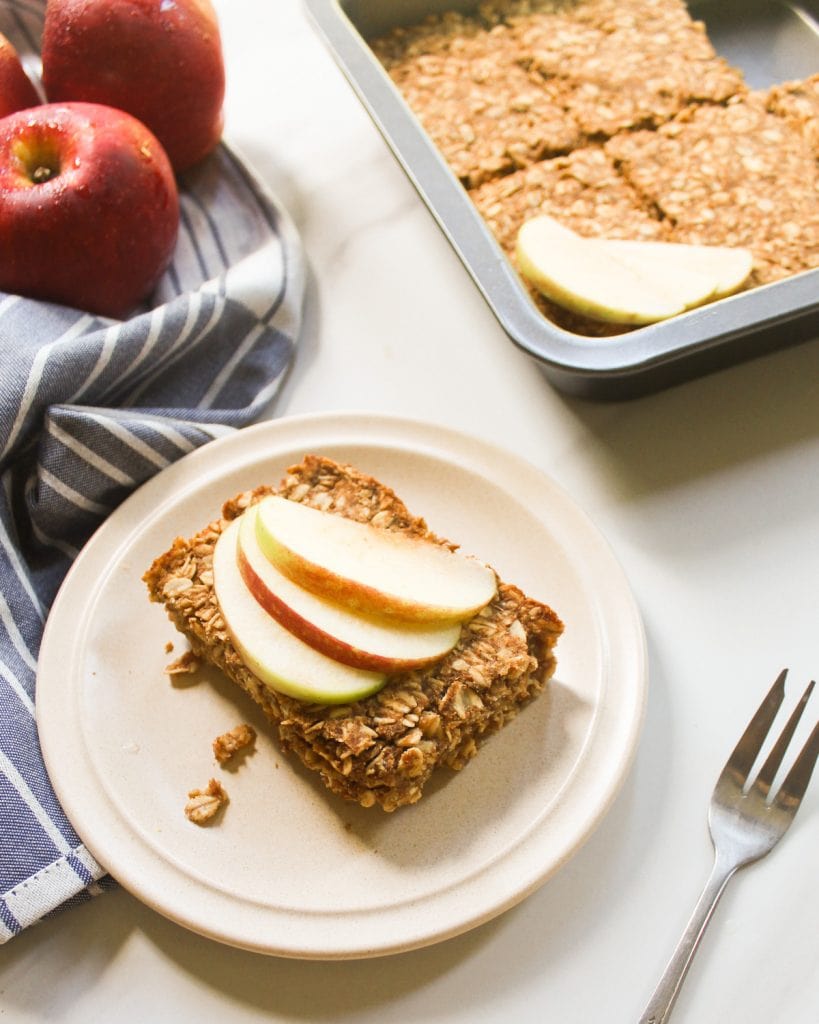 A side view of baked oatmeal serve on a small plate topped with apple slices.
