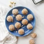 Bliss balls arranged on a blue plate with cashews in the background