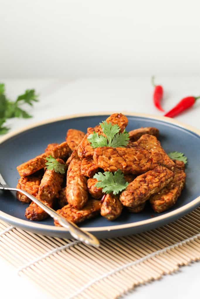 Close-up shot of tempeh served in a blue plate topped with cilantro leaves.