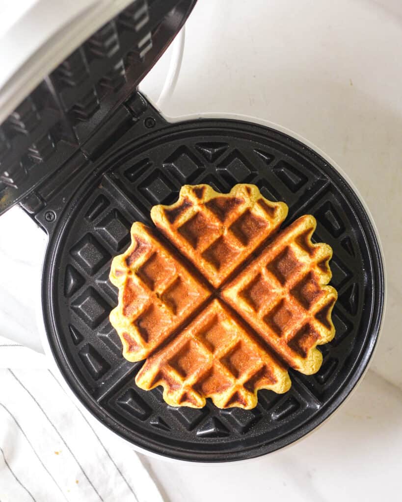 A freshly made waffle in a Belgium waffle maker.