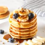 A head on look of a stack of chickpea flour pancake with maple syrup dripping down the sides.