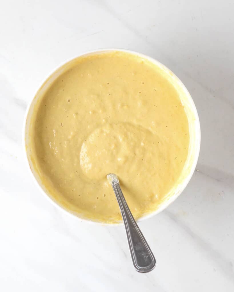 Batter of chickpea waffles in a white bowl with a fork.