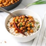Chickpeas served on a bed of brown rice in a bowl with a spoon