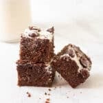 A close up shot of 2 brownies stacked on top of one another.