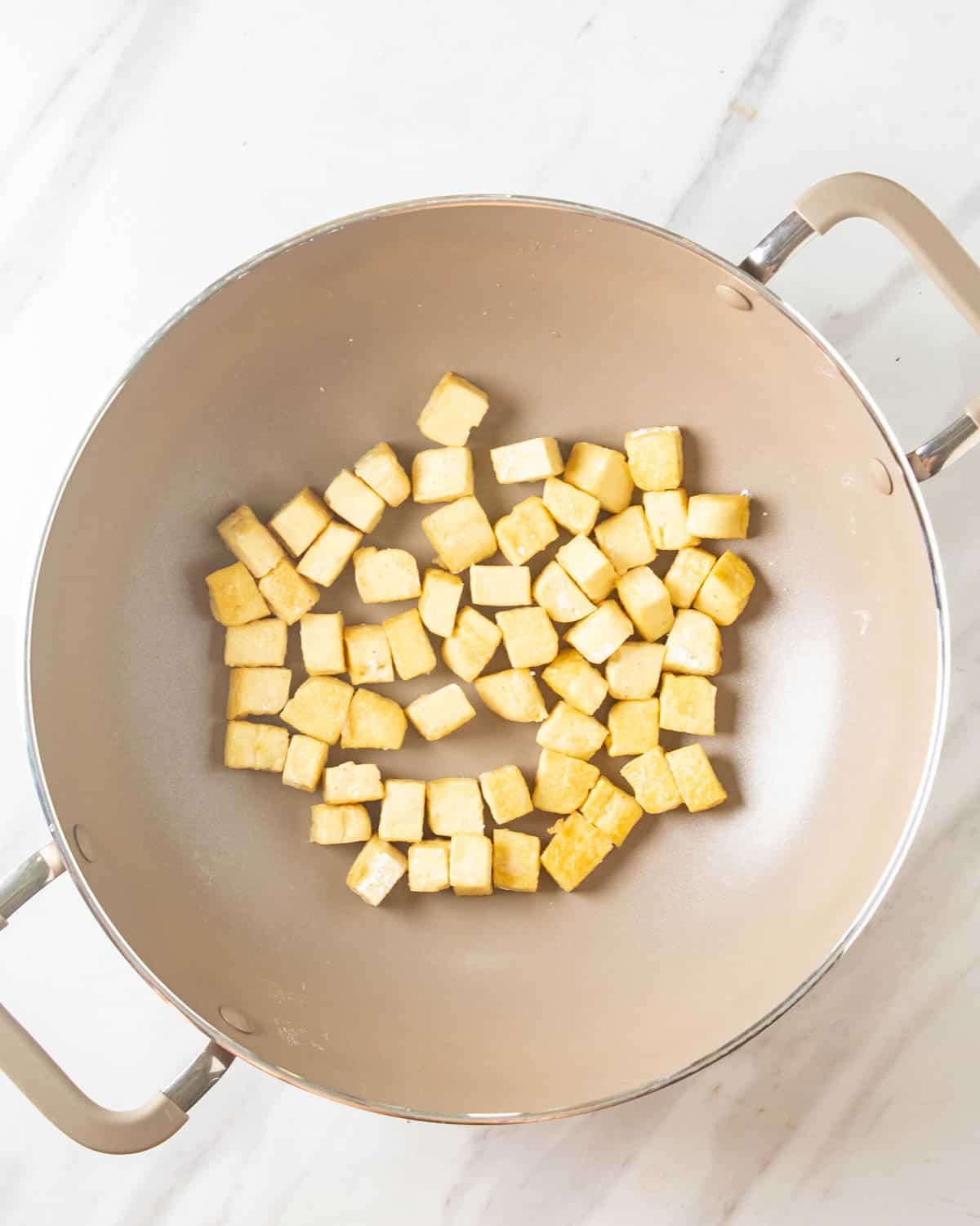 Pan frying tofu in a wok.