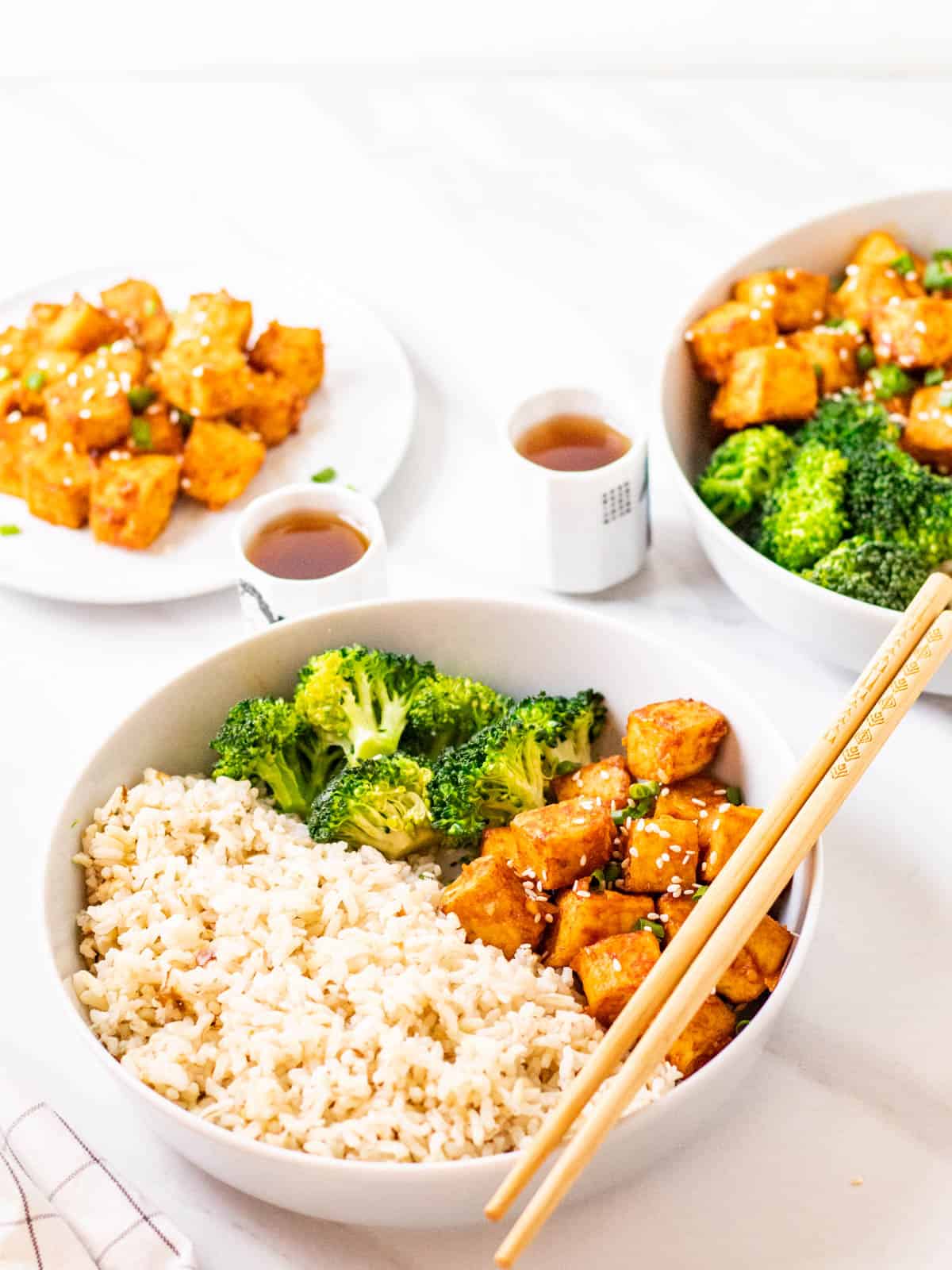 Close up shot of spicy korean tofu served with rice and broccoli with a pair of chopsticks on the side.