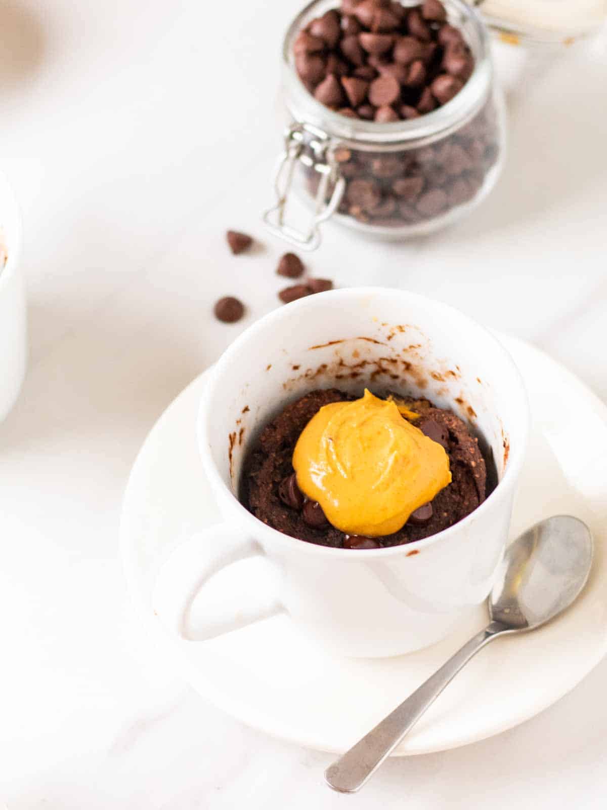 A head on shot of chocolate protein mug cake with a spoon on the side.