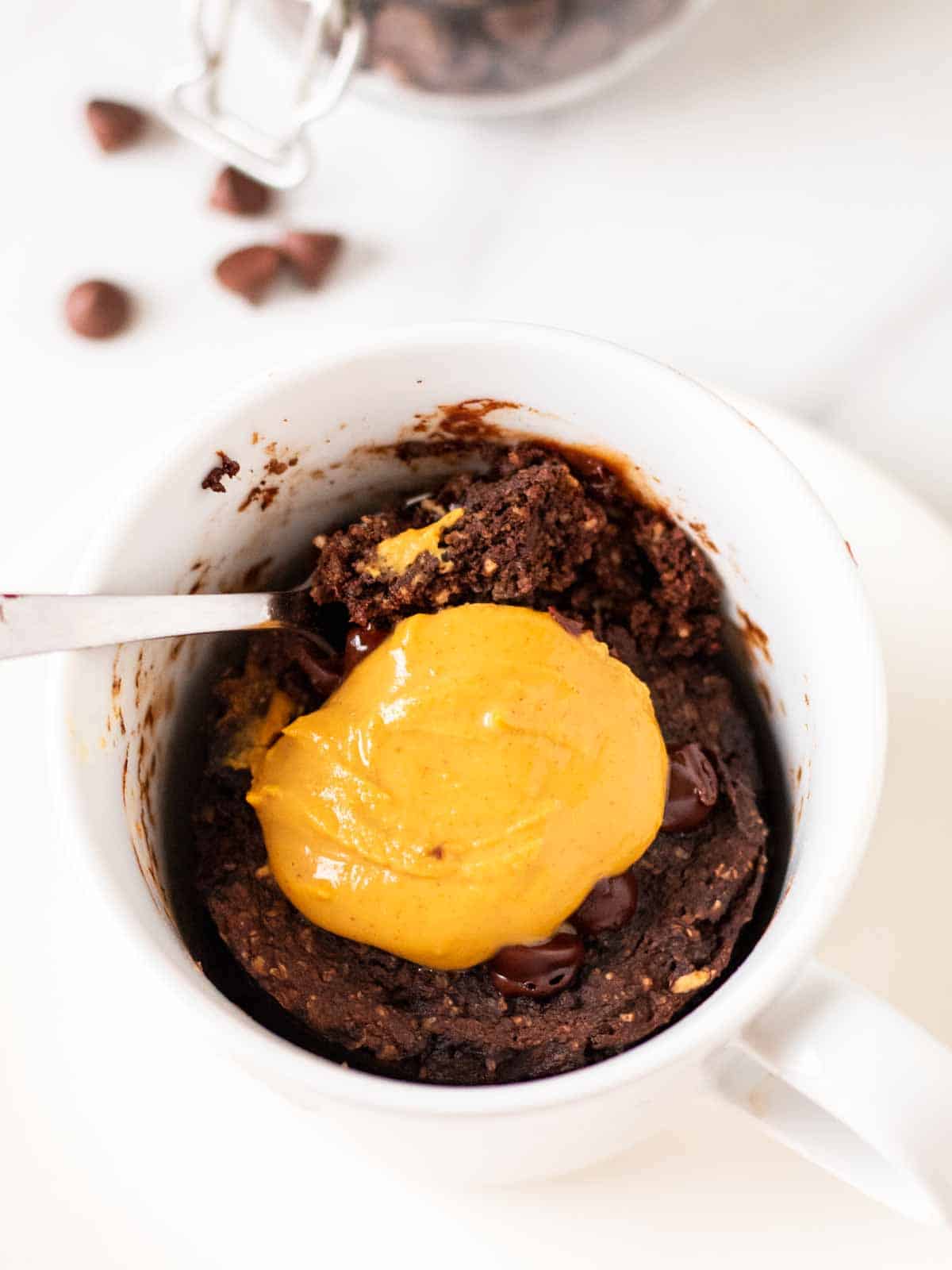 Spooning out a bite of chocolate protein mug cake from the mug.
