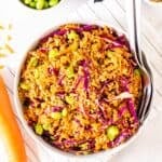 Thai quinoa cabbage salad served in a deep plate with large serving fork and spoon beside it.
