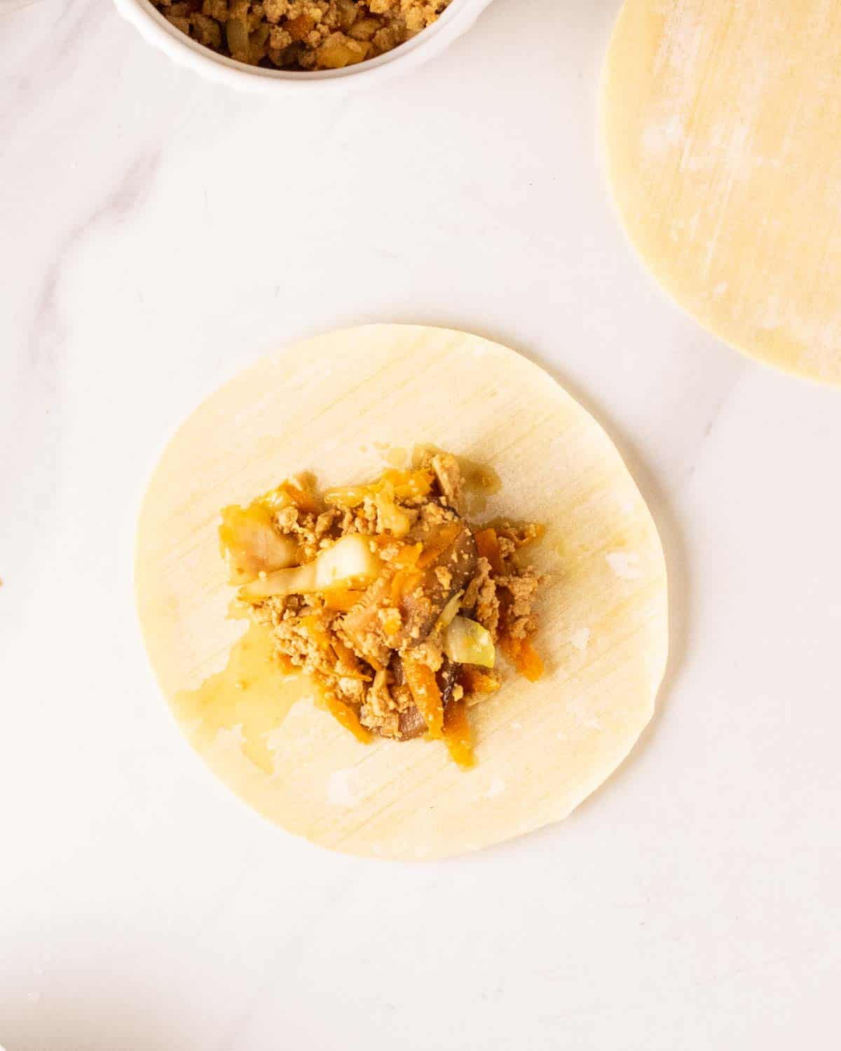 Adding filling at the center of the dumpling wrapper.