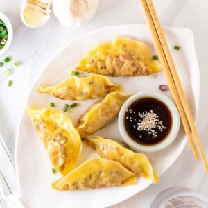 Vegan dumplings served on a plate with a pair of chopsticks on the side.