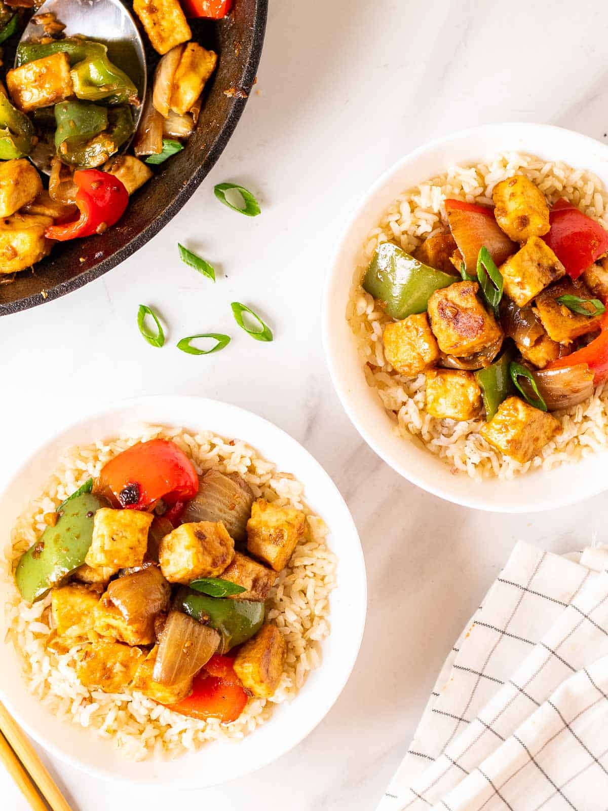 2 bowls of rice topped with black bean sauce tofu .