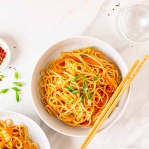 An overhead shot of noodles served in a deep plate with a pair of chopsticks on the side.