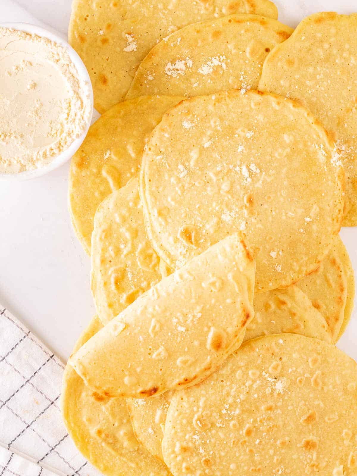 An overhead shot of chickpea flour tortillas on a white background.