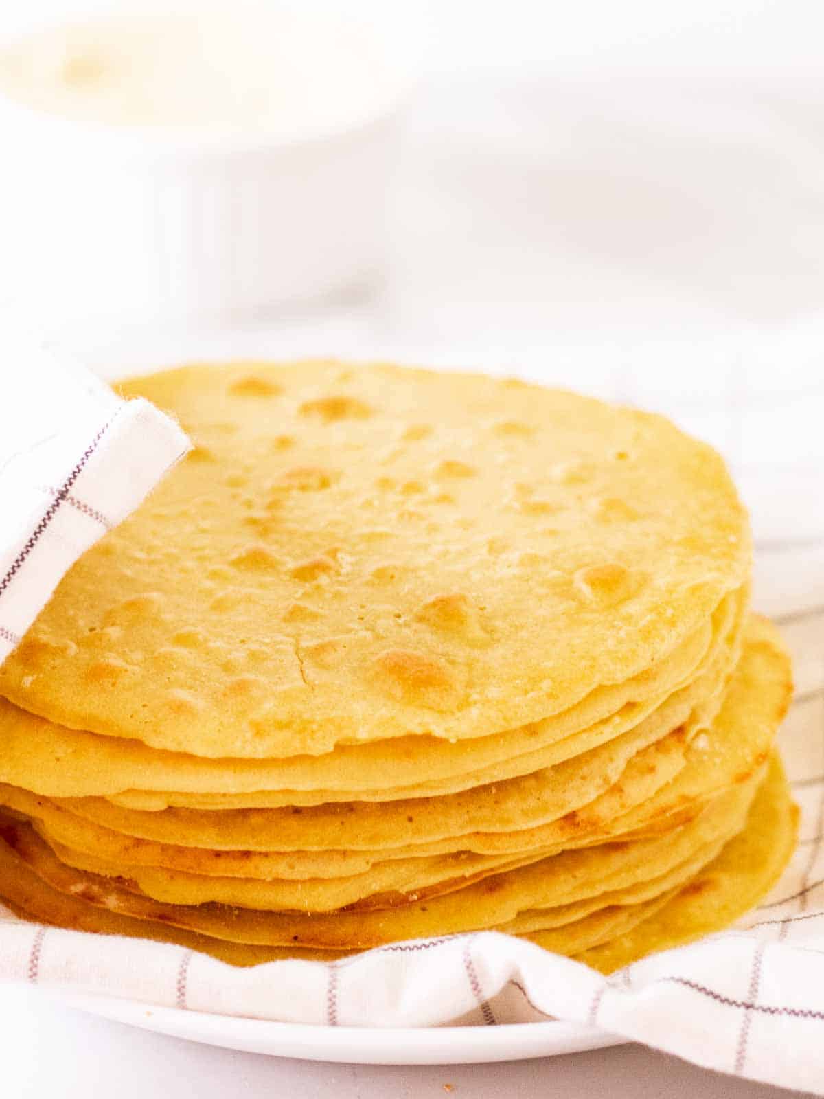 A stack of chickpea flour tortillas covered with a table cloth.