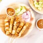 Tofu satay skewers served with peanut sauce and chopped raw vegetables.