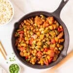 Overhead shot of sweet and sour chickpeas in a black skillet.