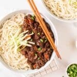 A close up shot of a bowl of jajangmyeon with chopsticks on the side.
