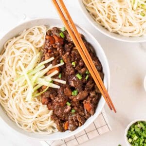 A close up shot of a bowl of jajangmyeon with chopsticks on the side.