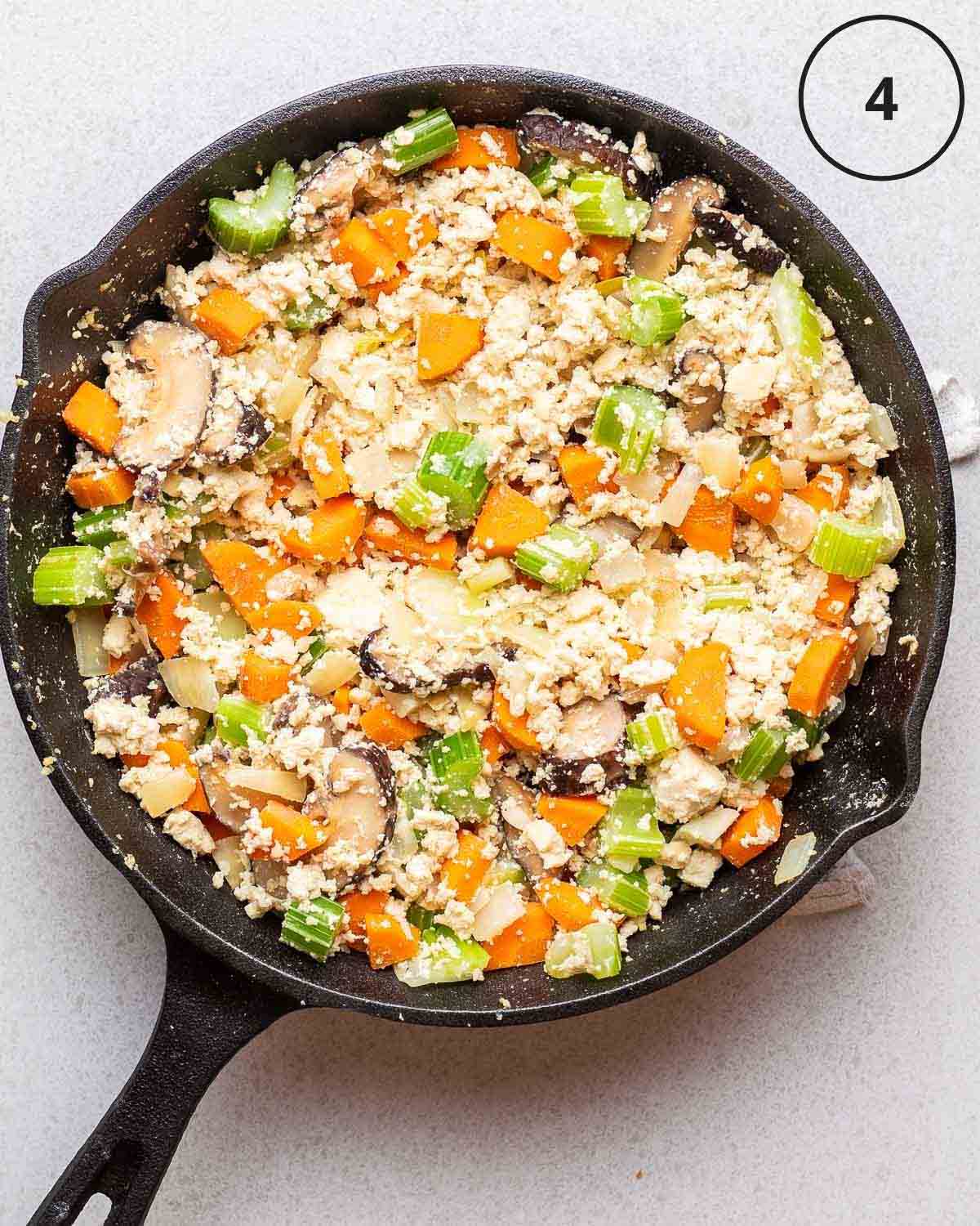 Showing cooking tofu and vegetables in a black pan.