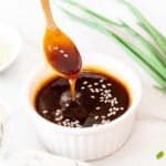 Spooning teriyaki sauce from a white ramekin.