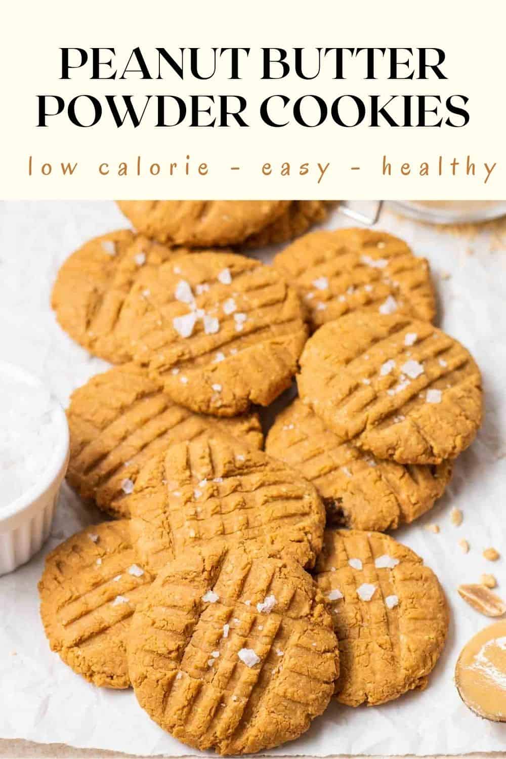 Peanut cookies on a white background topped with sea salt flakes with text on the upper half.