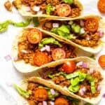 A few tacos arranged on a parchment paper.