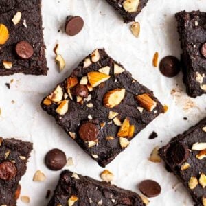 Slices of brownies arranged on a parchment paper with chocolate chips in the background.