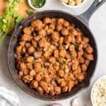 A pan of soya chunks masala topped with chopped cilantro with bowl of rice and cilantro beside.