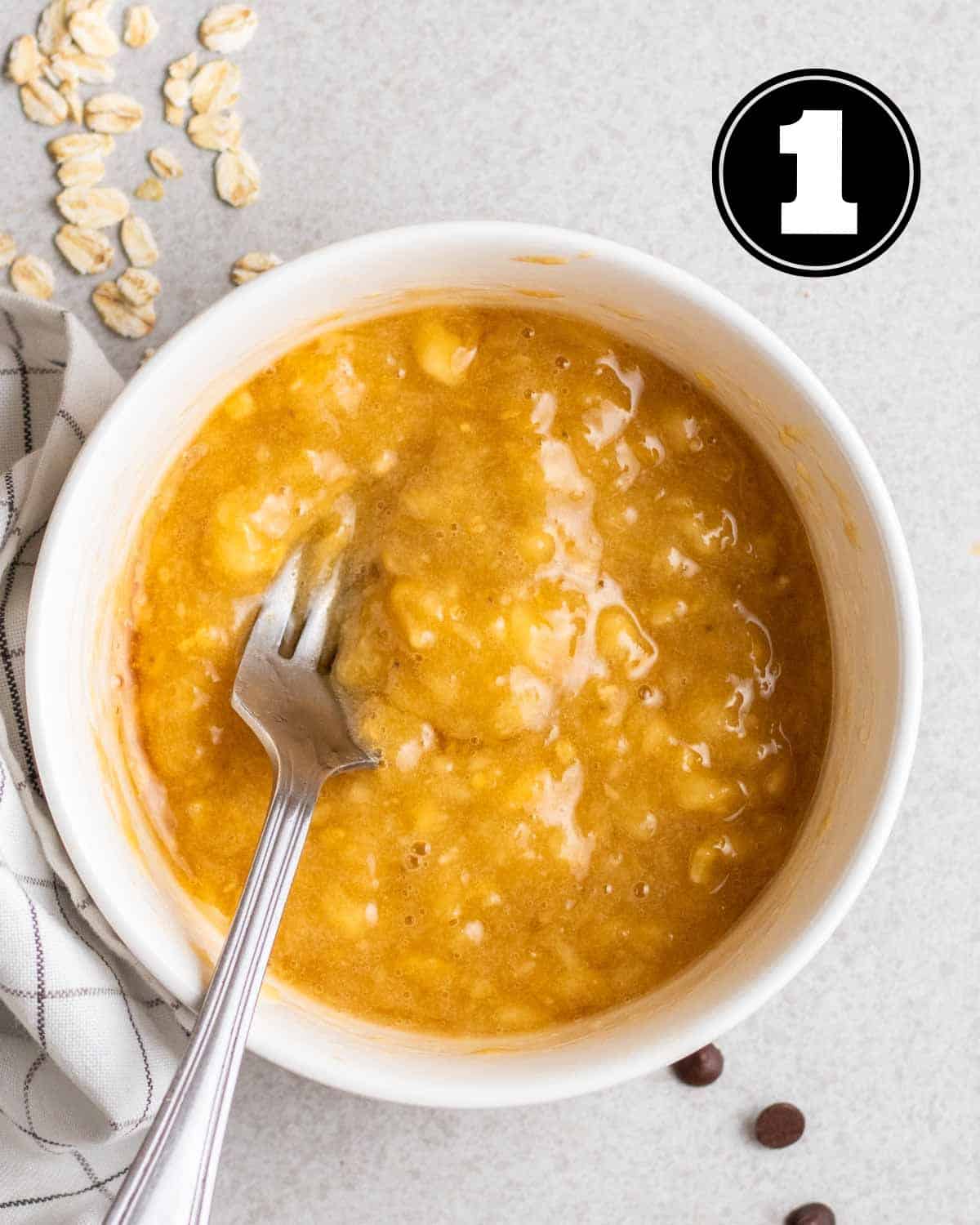 Mashed bananas in a ramekin with a fork beside.