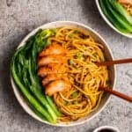 Bowl of wonton noodles with choy sum and vegan roast pork beside with chopsticks.