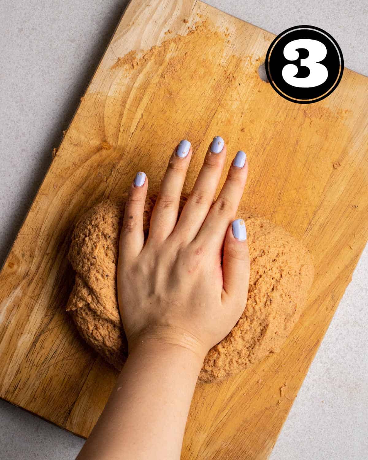 Kneading seitan dough on a wooden chopping board.