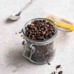 Jar of roasted black beans with a spoon in the background.