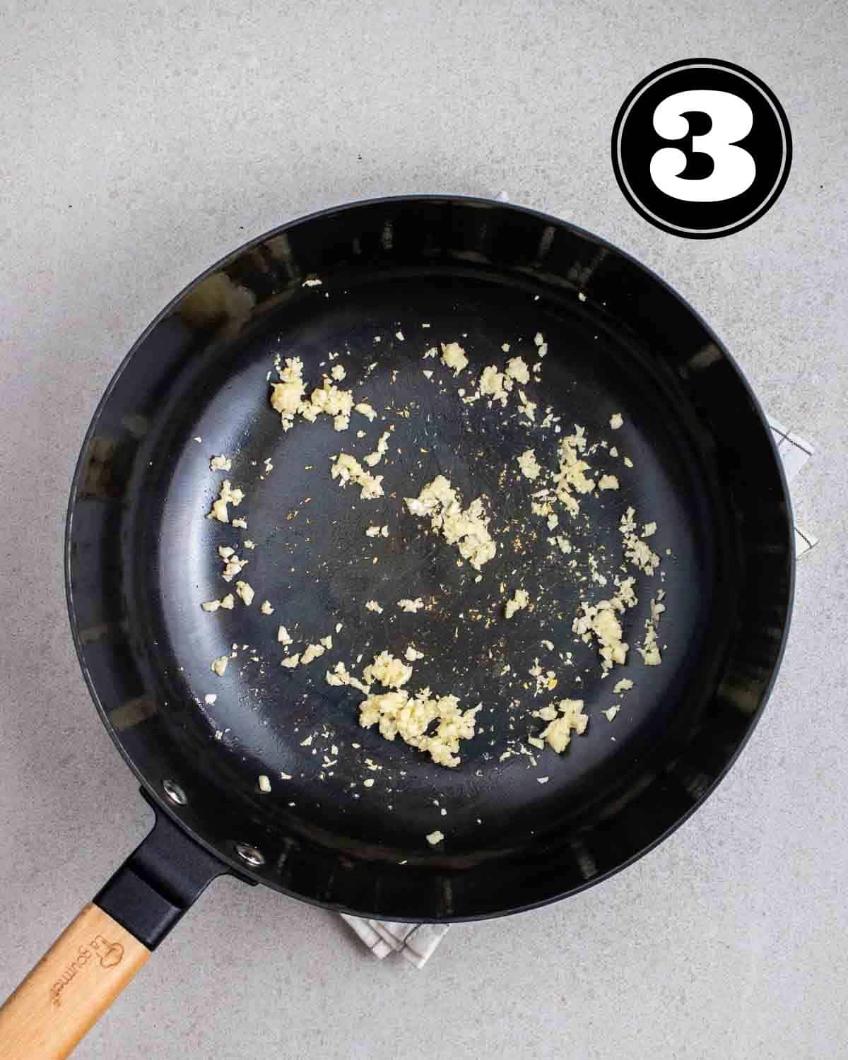 Fried garlic in a wok on a folded white teacloth.