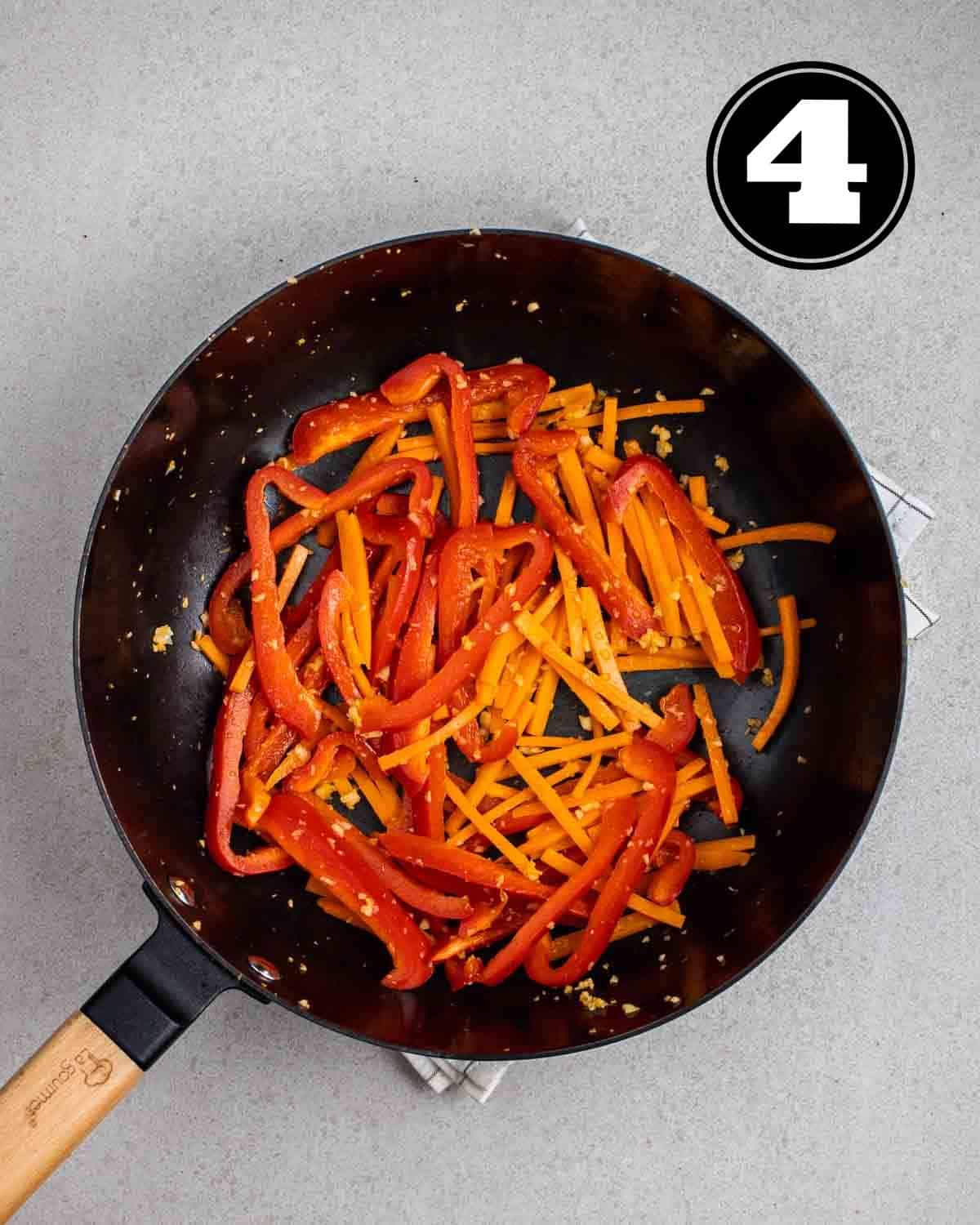 Cooked bell peppers and carrots in a wok.