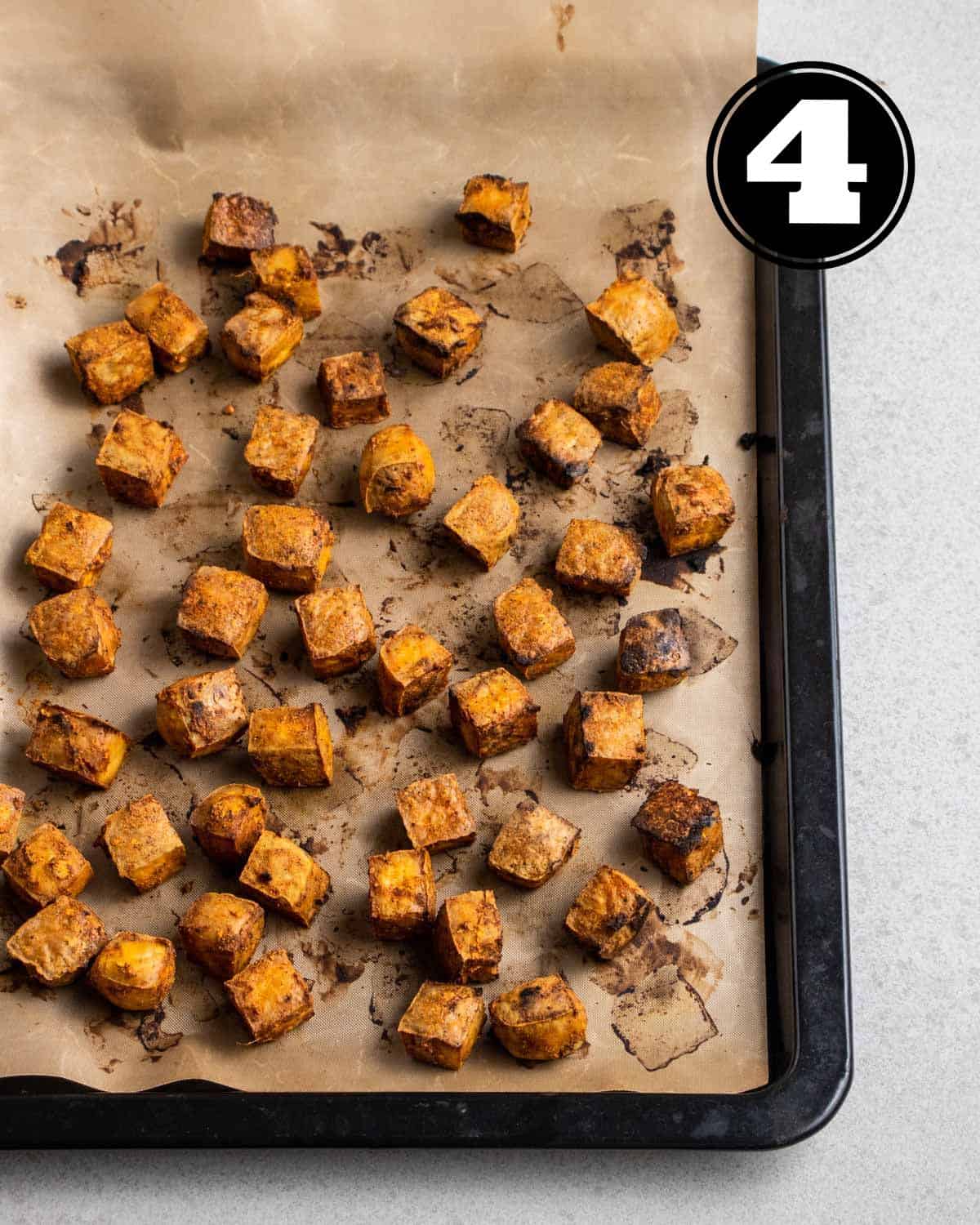 Baked tandoori tofu in a black baking tray lined with parchment paper.