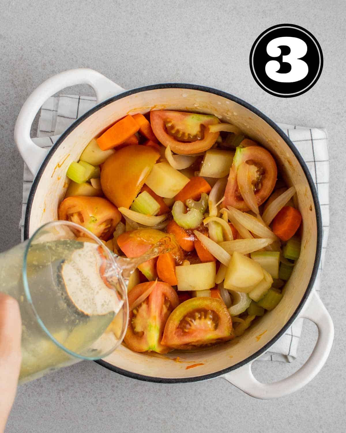 Pouring broth in a pot of cooked vegetables.