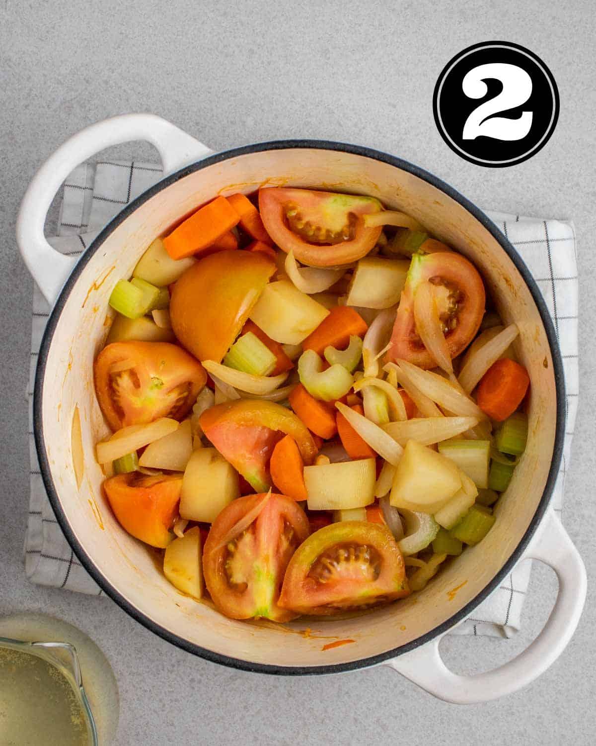 Sauteed veggies in a white Dutch oven.