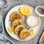 A plate of chickpea patties served with yogurt and lemon slices.