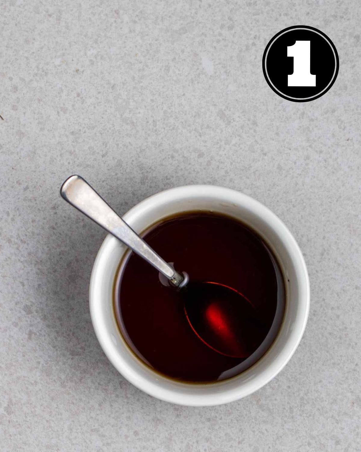 Sesame soy dressing in a white ramekin with a teaspoon beside.