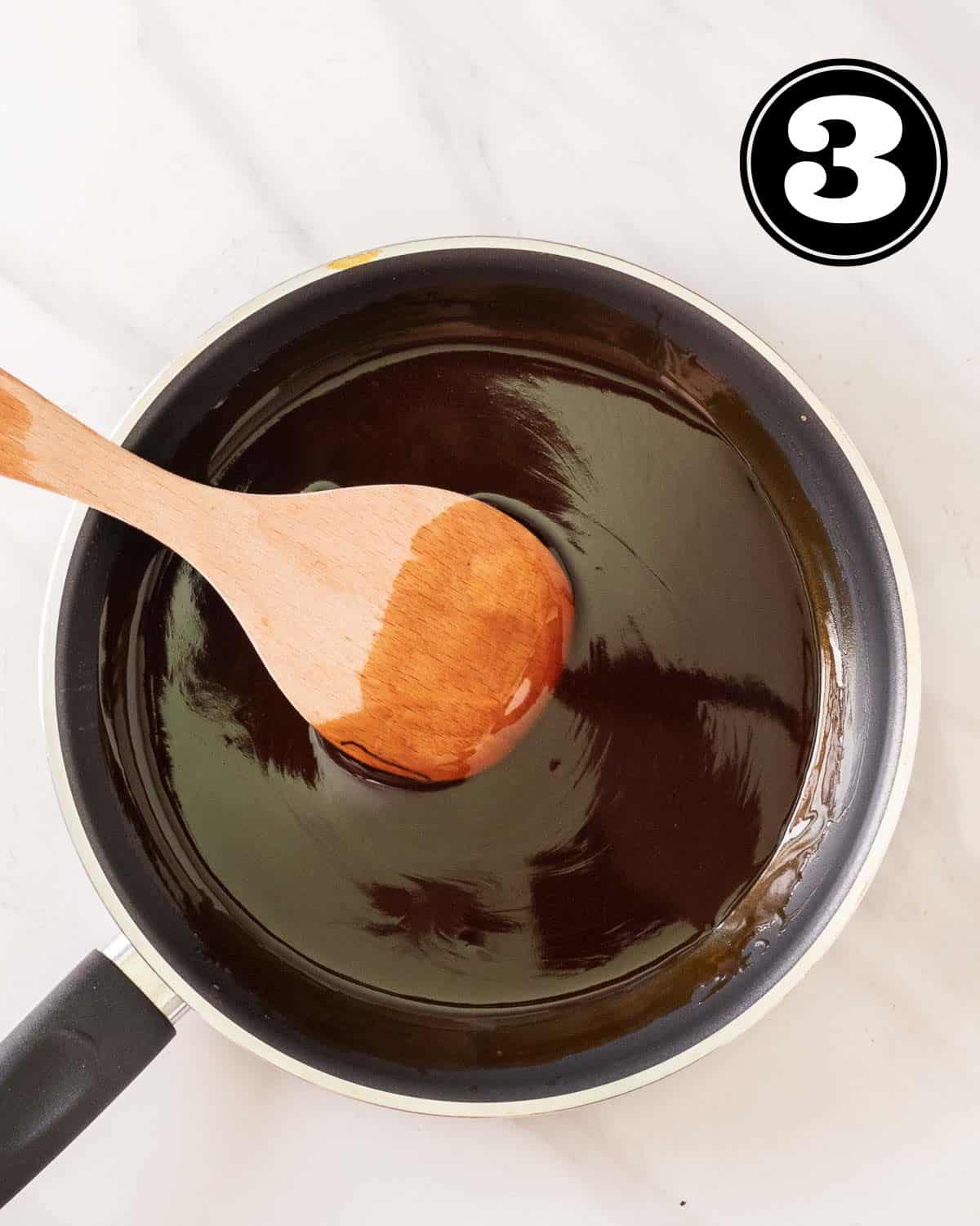 A pan of teriyaki sauce with a wooden spatula beside.