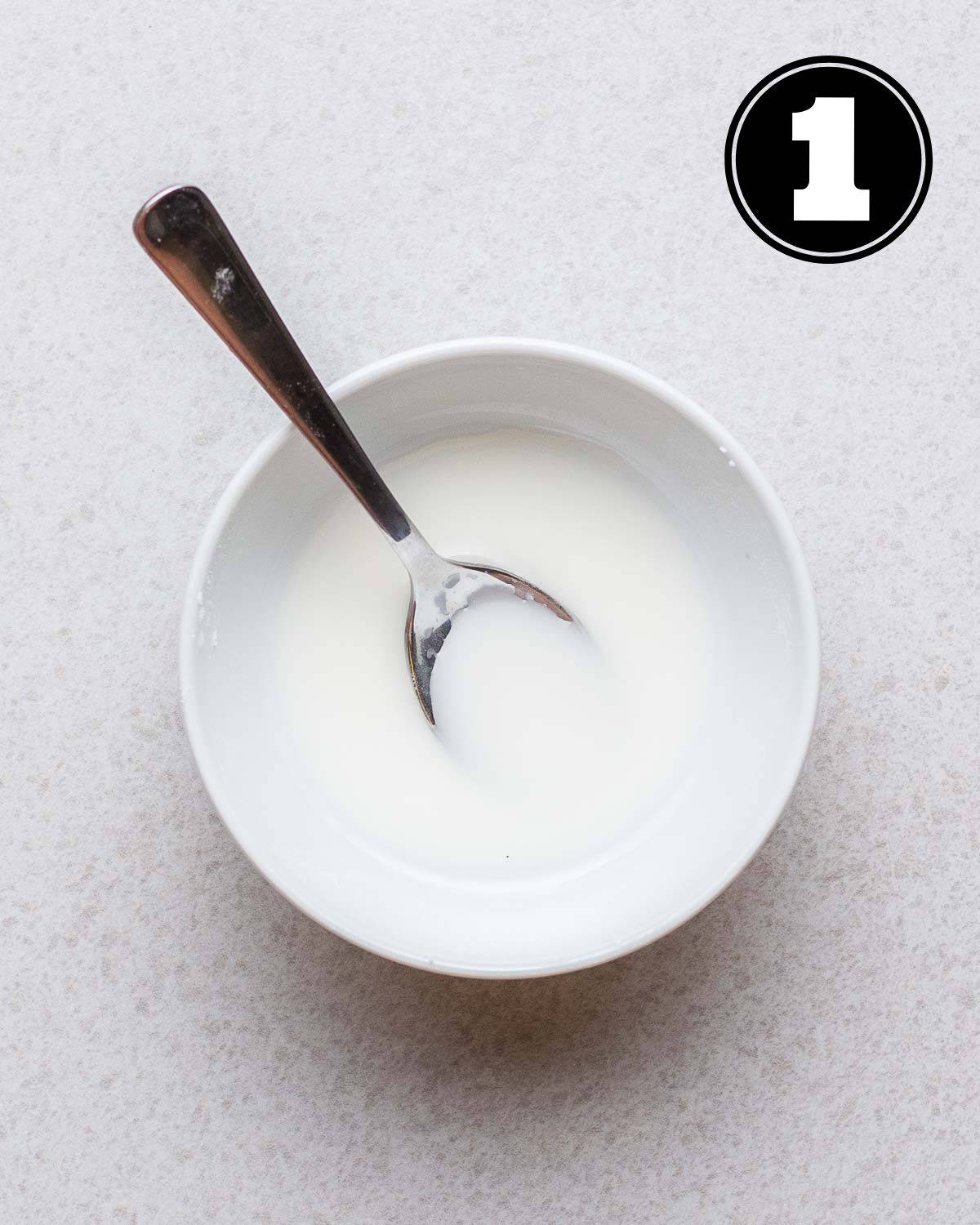 Cornstarch slurry in a bowl with a teaspoon beside.