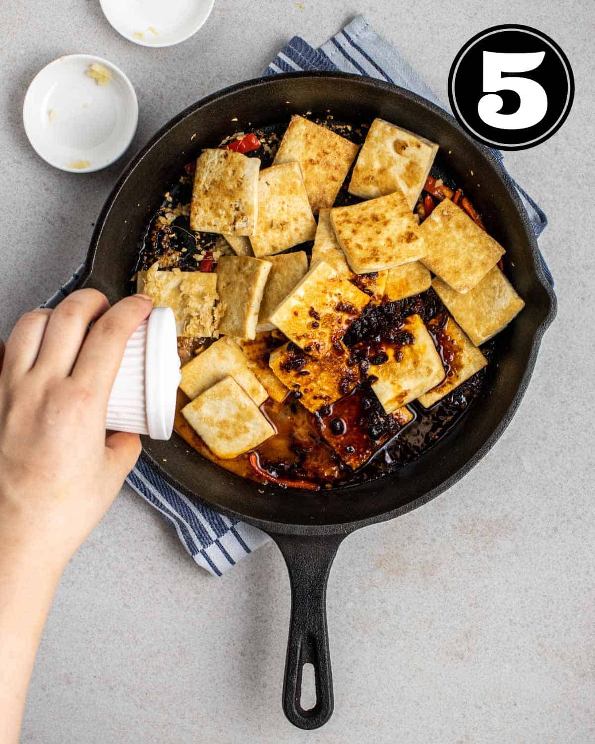 Pouring slurry into a pan of tofu and aromatics.