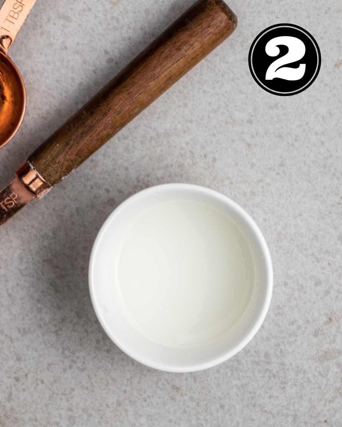 Cornstarch slurry in a ramekin with 2 teaspoons beside.