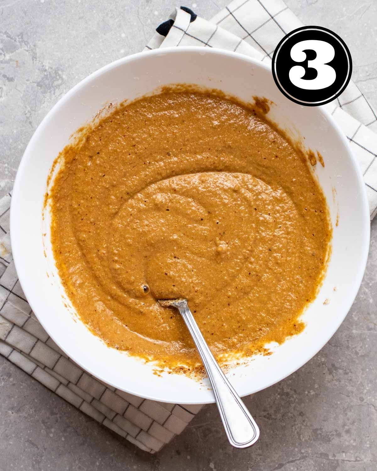 Coffee cake batter in a white bowl with a spoon beside.