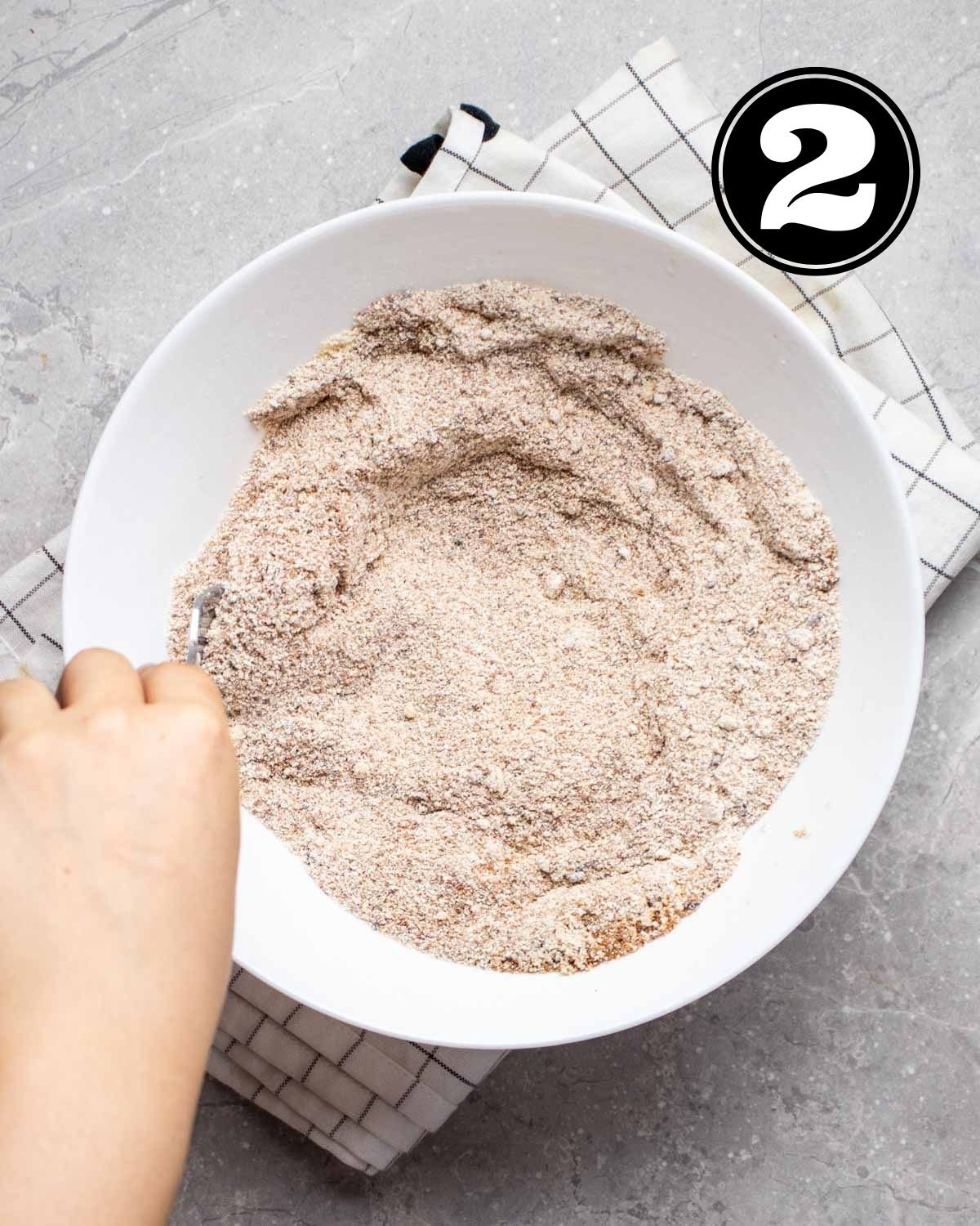 Combining dry ingredients in a white mixing bowl. 