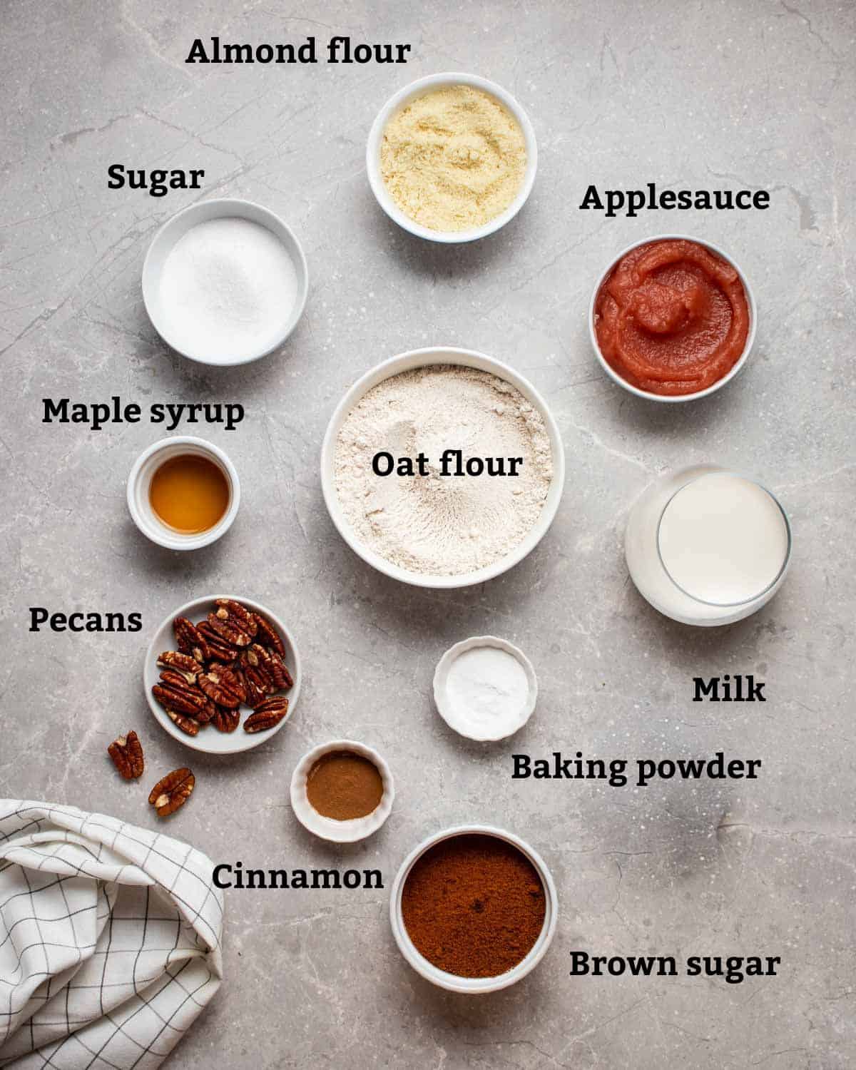 Ingredients needed for coffee cake such as almond flour, oat flour, applesauce, brown sugar, and pecans.